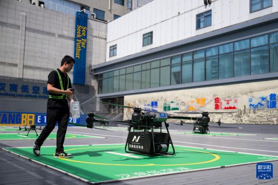6月16日,在汉商低空港停机坪,一名工作人员给无人机装配货物。新华社记者 伍志尊 摄